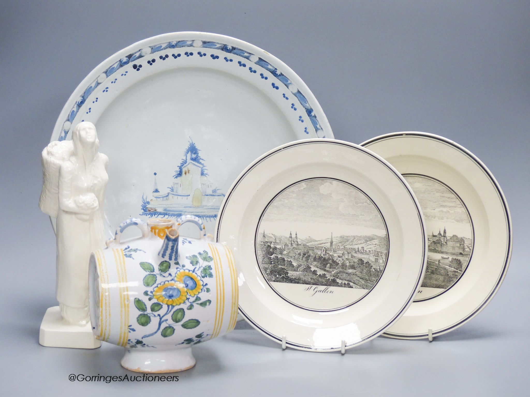 A Continental tin glaze dish, 18th/19th century, possibly Portuguese, a faience Gin barrel, a pottery figure, inscribed in pencil ‘I Barry’ and two Zell Creamware topographical plates
